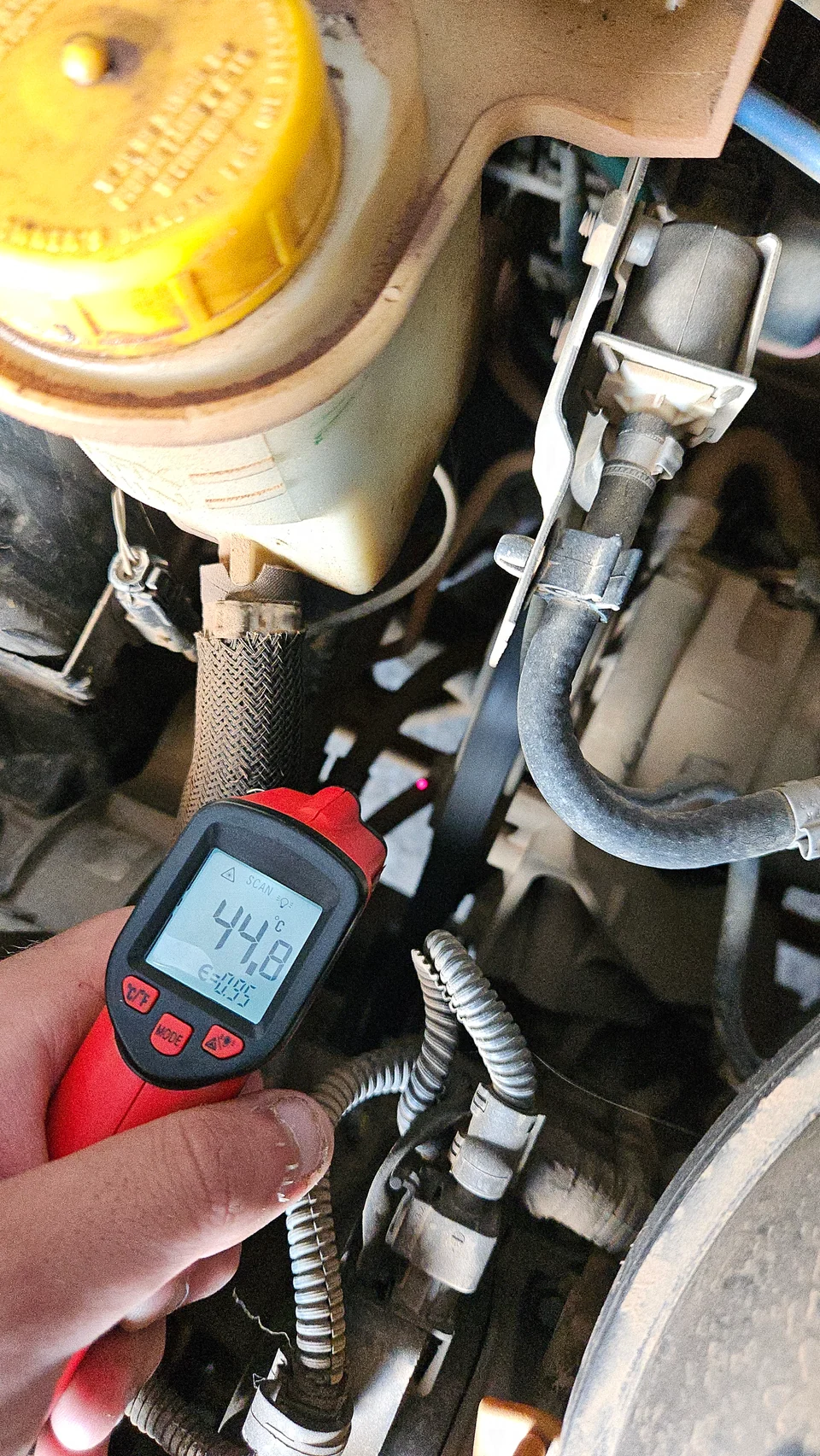 Medição com termômetro infravermelho durante inspeção de componentes no compartimento do motor